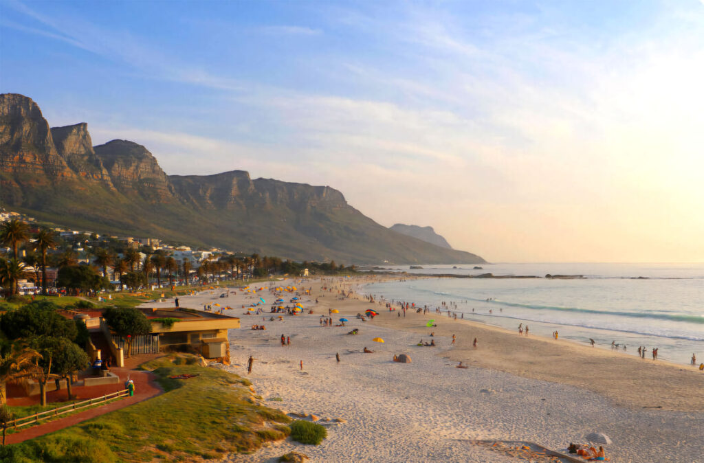 An image of a beach view in cape town with a mountain in the horizon and a clear sky